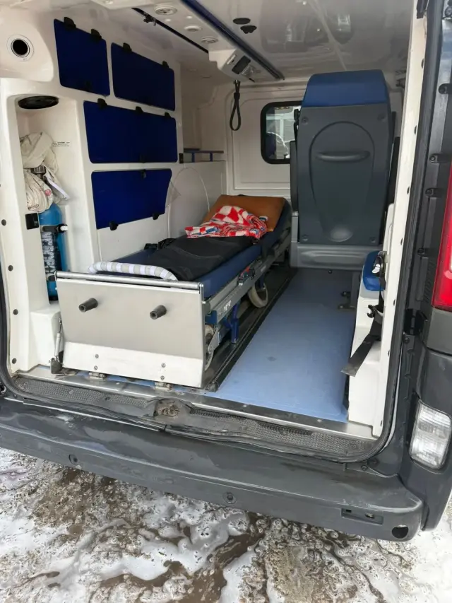 Салон санітарного автомобіля з боку задніх дверей: медичні ноші на напрямних, кисневий балон, крісло супроводжуючого та платформа для завантаження лежачих пацієнтів.